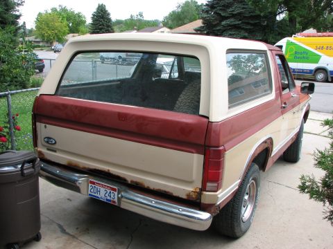 1986 Ford Bronco - This two-tone Ford Bronco shows significant rust on its rear bumper and body panels, indicating its age and condition.