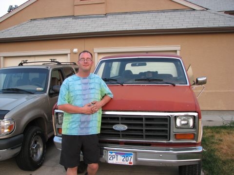1986 Ford Bronco - A man stands next to a red Ford van, with another SUV to the left.
