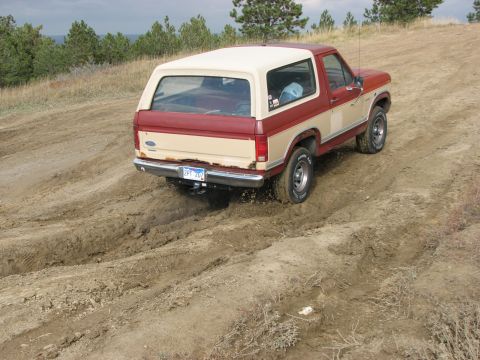 1986 Ford Bronco - 1986 Ford Bronco navigating a muddy off-road trail.