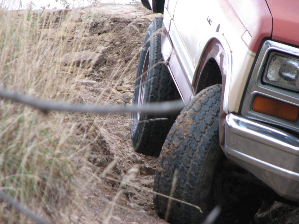 Red and white SUV with off-road tires on a dirt path