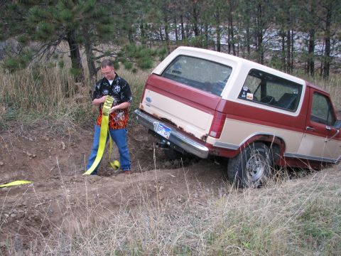 1986 Ford Bronco - A man prepares to tow a stuck Ford Bronco off-road.