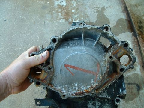 1995 Ford Bronco - A hand holds a corroded water pump housing with a red arrow marked '1' on its surface.