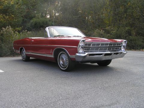 1967 Ford Galaxie - A red 1967 Ford Galaxie convertible is parked outdoors with trees in the background.