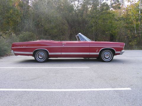 1967 Ford Galaxie - A red 1967 Ford Galaxie convertible is parked in a lot, viewed from the side.