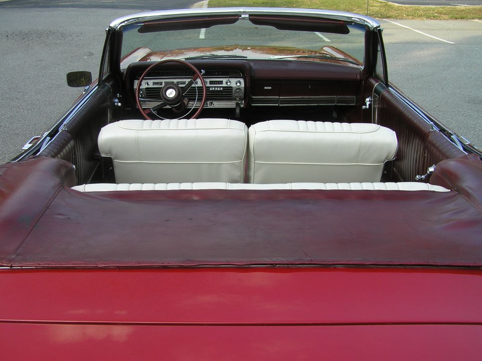 Rear view into red convertible with white seats and maroon interior, top down