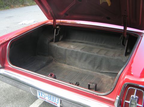 1967 Ford Galaxie - The trunk of a red car is open, revealing its storage space and a license plate.