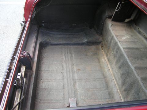 1967 Ford Galaxie - The interior of a car trunk is shown from a rear-facing angle, revealing the carpeted floor and side panels.