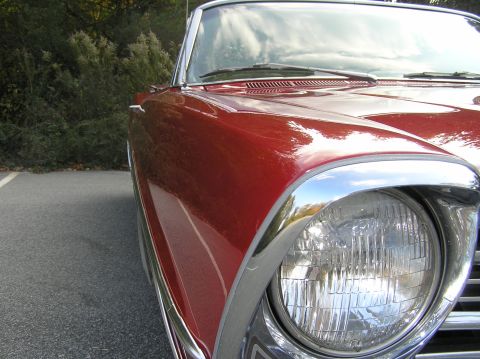 1967 Ford Galaxie - Close-up of the front corner of a red 1967 Ford Galaxie convertible, highlighting its chrome accents and headlight.