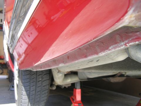 1967 Ford Galaxie - Underside view of a red car, showing the rocker panel, exhaust, and a jack.