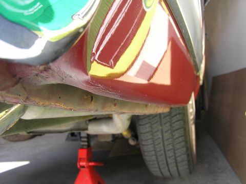 1967 Ford Galaxie - The underside of a red vehicle is visible, supported by a red jack, with signs of rust on the frame.