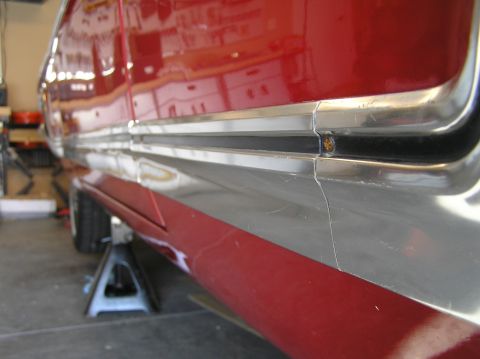 1967 Ford Galaxie - The side trim of a red vehicle is shown, with a visible screw holding it in place.