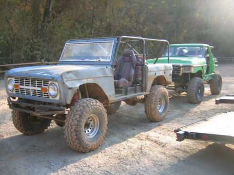 1992 Ford Mustang - A modified gray Ford Bronco is seen towing a green pickup truck on a dirt road.