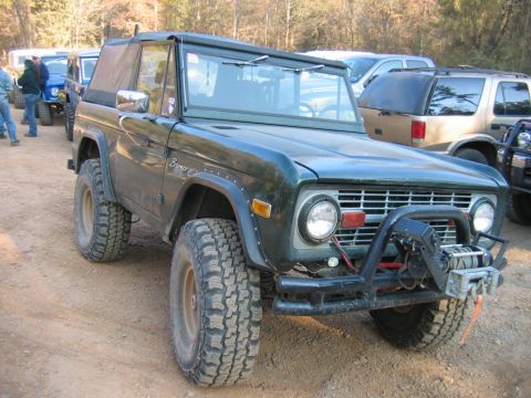 1992 Ford Mustang - A dark green Ford Bronco is parked on a dirt road with other vehicles in the background.