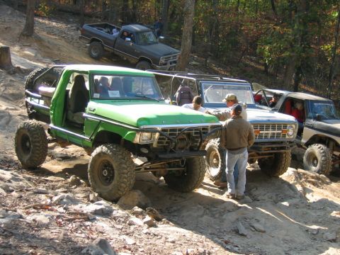 1992 Ford Mustang - Several off-road vehicles, including a green pickup and a blue Bronco, navigate a rocky trail.