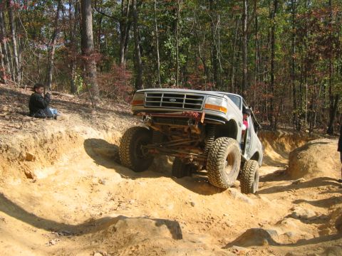 1992 Ford Mustang - A lifted 1992 Ford Bronco navigates a challenging off-road course with steep inclines and rocky terrain.