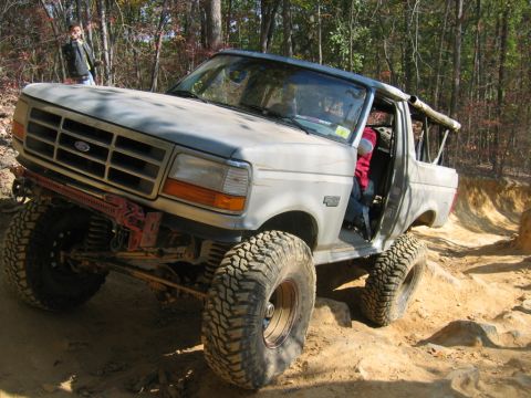 1992 Ford Mustang - A lifted 1992 Ford Bronco navigates a challenging off-road trail with large tires and a modified suspension.