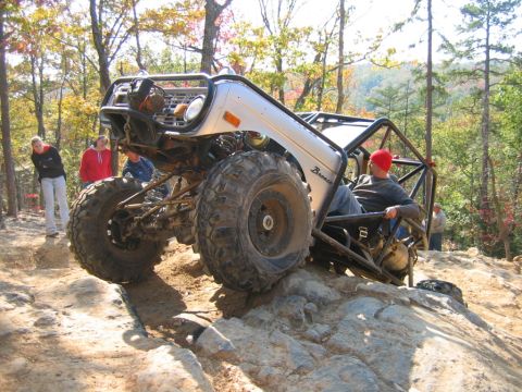 1992 Ford Mustang - This heavily modified Bronco is navigating a rocky trail with spectators observing the challenging climb.