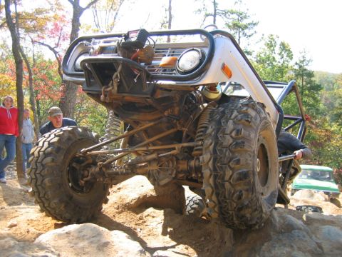 1992 Ford Mustang - Modified off-road vehicle navigating rocky terrain with people watching.