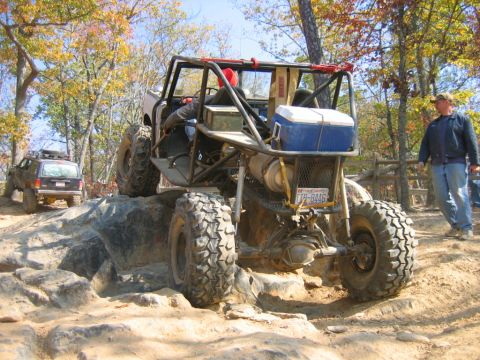 1992 Ford Mustang - A custom-built off-road buggy navigates a rocky trail, with another SUV visible in the background.