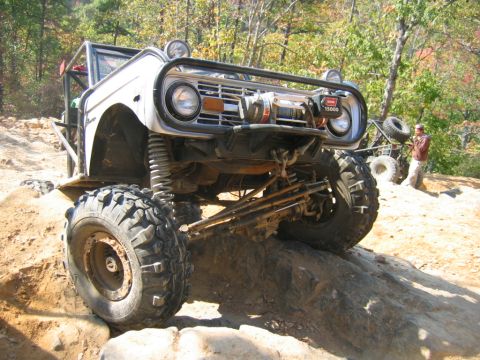 1992 Ford Mustang - A heavily modified Ford Bronco navigates a rocky off-road trail with a winch mounted on the front.