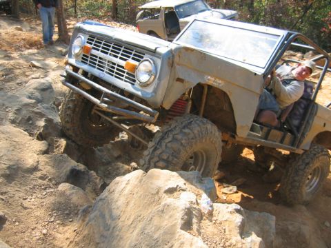 1992 Ford Mustang - A modified Ford Bronco tackles a challenging off-road course with another vehicle in the background.