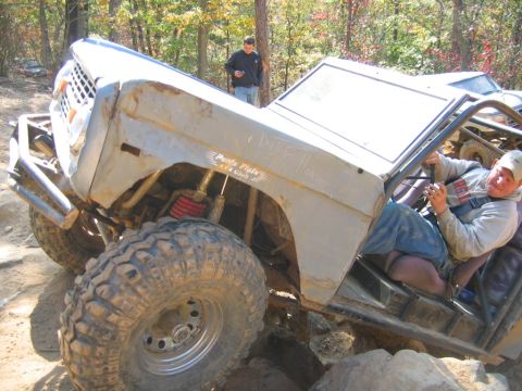 1992 Ford Mustang - Modified off-road vehicle navigating difficult terrain with a driver inside.