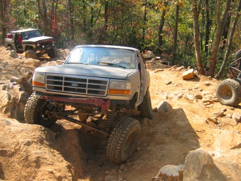 1992 Ford Mustang - A modified 1992 Ford F-150 navigates a challenging off-road trail with another vehicle visible in the background.