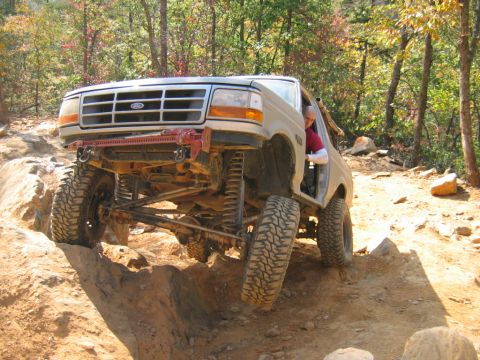 1992 Ford Mustang - Modified Ford Bronco tackles a challenging off-road trail with steep inclines and rocky terrain.