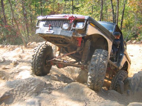 1992 Ford Mustang - This heavily modified off-road vehicle is shown tackling a challenging rocky terrain.