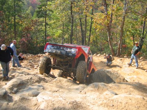 1992 Ford Mustang - A red Bronco navigates a challenging rocky terrain with onlookers observing the off-road action.