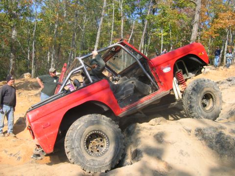 1992 Ford Mustang - A red Bronco with a roll cage navigates a rocky terrain, demonstrating its off-road capabilities.