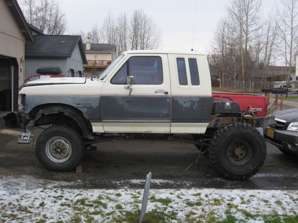 1990 Ford F-250 extended cab truck with large off-road tires, lifted suspension, and custom rear end