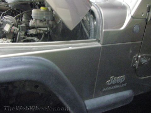 1987 Suzuki Samurai - Close-up of a Jeep Scrambler, revealing its engine compartment and side panel.