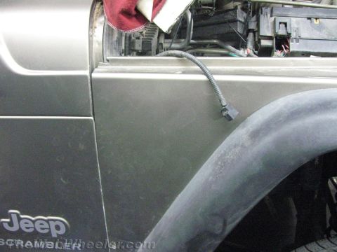 1987 Suzuki Samurai - Close-up of a Jeep's fender and exposed engine components, with a red cloth covering part of the engine.