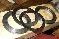 1996 Ford Bronco - Four metal rings with rubber seals are laid out on a wooden surface.