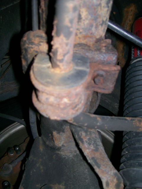 1995 Mercury Grand Marquis - Close-up of a heavily rusted suspension component, likely a sway bar link, showing wear and corrosion.