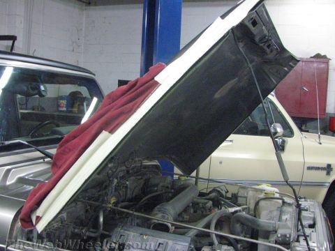 1987 Suzuki Samurai - The engine bay of a silver Jeep Wrangler is exposed, with a red cloth draped over the open hood.