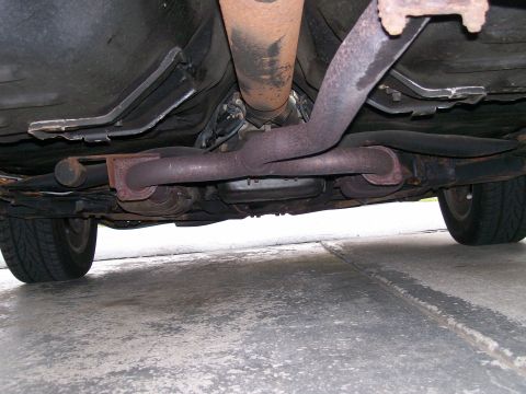 1995 Mercury Grand Marquis - Underside view of a vehicle's exhaust system, driveshaft, and rear tire.