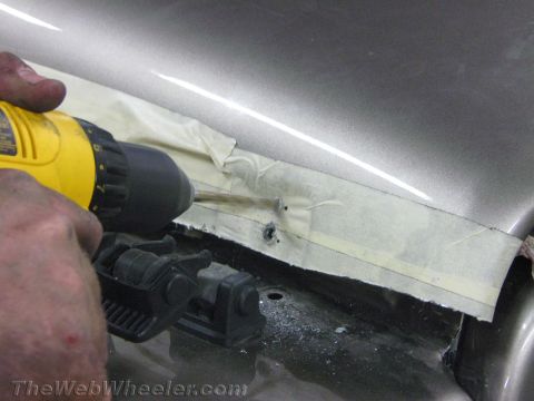 1987 Suzuki Samurai - A person drills into a taped section of a grey car's hood.