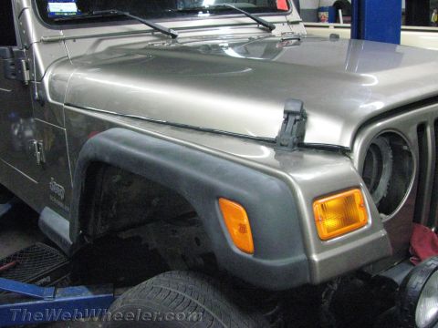 1987 Suzuki Samurai - Close-up of a tan Jeep Wrangler's front fender, showing the fender flare and turn signal light.
