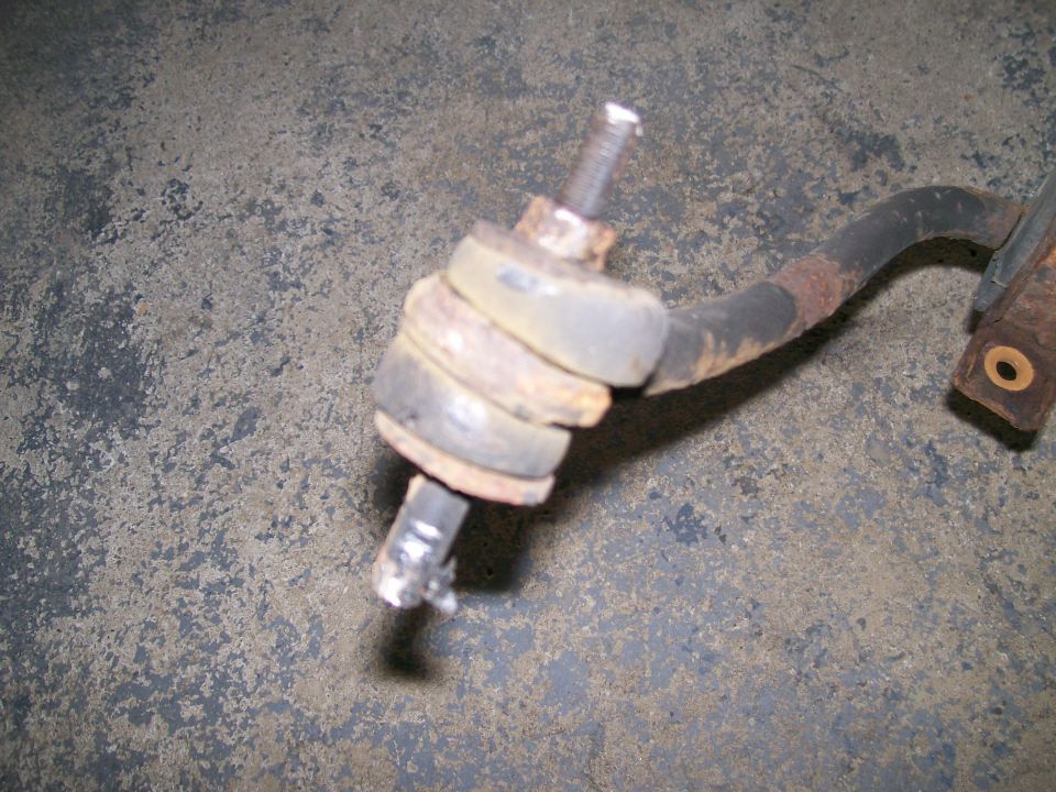 Rusty sway bar end link with rubber bushings and a bolt, on a concrete surface