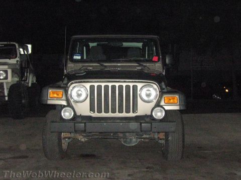 1987 Suzuki Samurai - A Jeep Wrangler is parked next to another vehicle at night.
