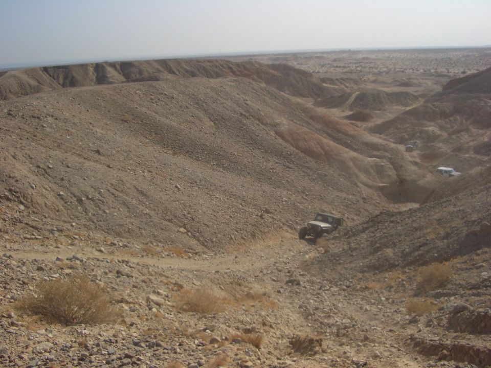 Off-road vehicles navigating a steep, rocky desert canyon