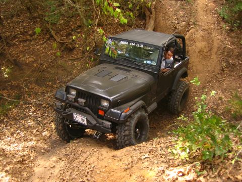2001 Jeep Wrangler - A dark gray Jeep Wrangler navigates a dirt trail, its front-left quarter visible as it climbs.