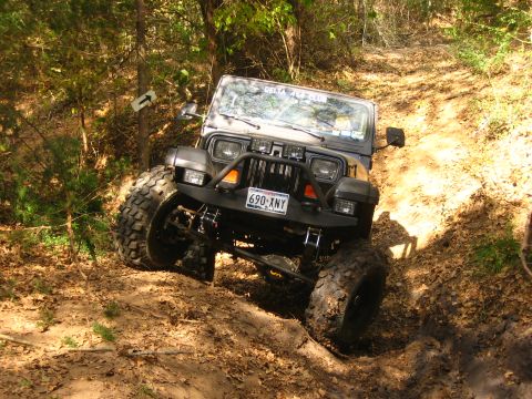 2001 Jeep Wrangler - A modified Jeep Wrangler navigates a steep, muddy incline on a wooded trail.