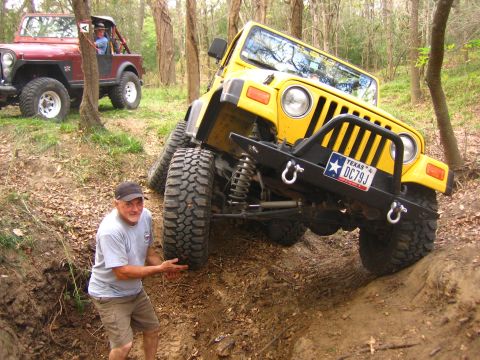 2001 Jeep Wrangler - A yellow 2001 Jeep Wrangler is shown navigating a challenging off-road terrain, with another Jeep visible in the background.