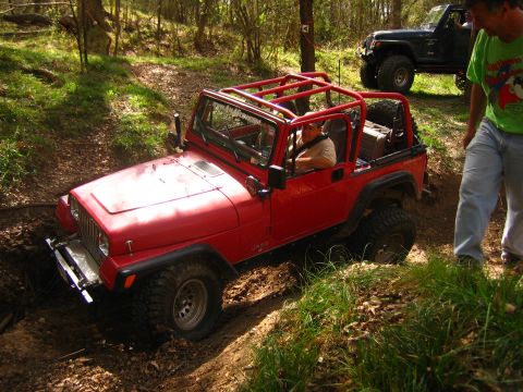 2001 Jeep Wrangler - A red Jeep Wrangler navigates a challenging off-road trail, with a second Jeep visible in the background.