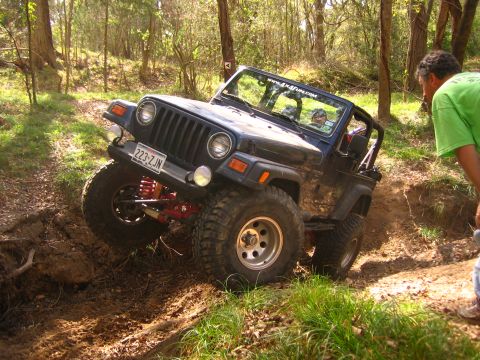 2001 Jeep Wrangler - A blue 2001 Jeep Wrangler navigates a challenging off-road trail with a spectator observing.