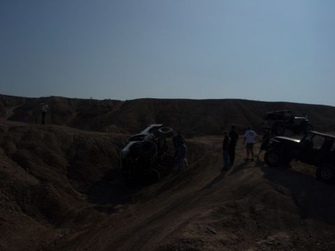 1985 Ford Bronco - Off-road vehicles gathered in a desert landscape with one vehicle overturned.