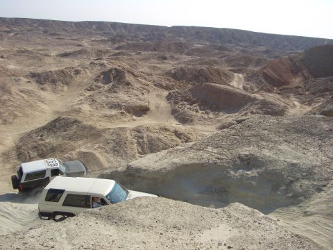 1985 Ford Bronco - Multiple off-road vehicles navigate a challenging desert terrain with steep inclines and sandy paths.